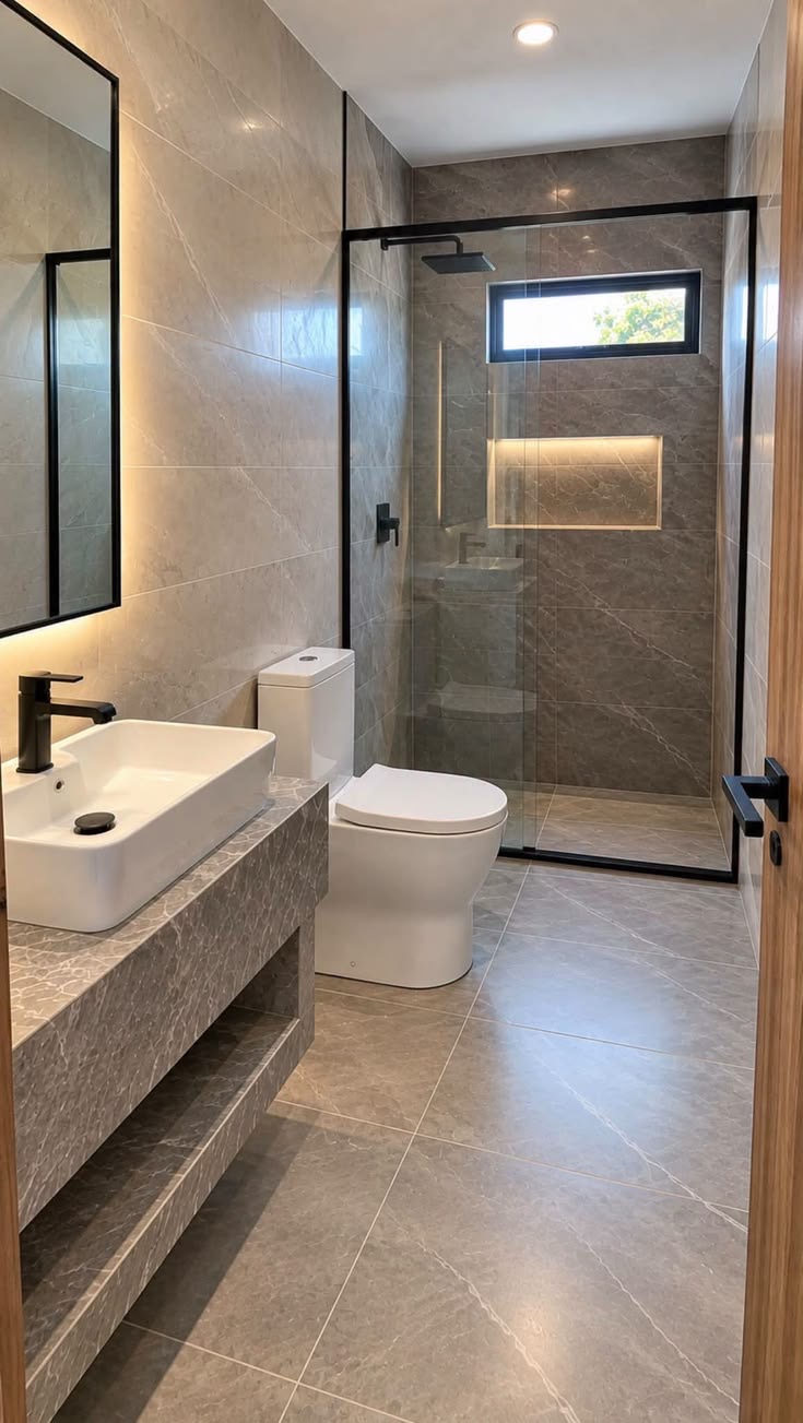 Casa de banho concluída com duche em vidro e revestimento cinzento